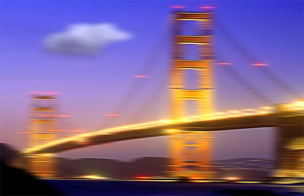 A blurred image of a large suspension bridge at dusk with a single cloud in the sky.